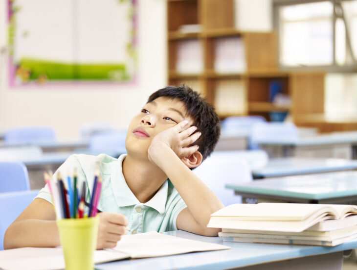 Asian pupil thinking in classroom