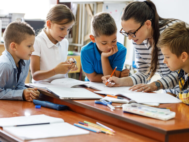 A kind female teacher spends time with her elementary school students, making learning enjoyable and fun while sparking curiosity and fostering a love for education.